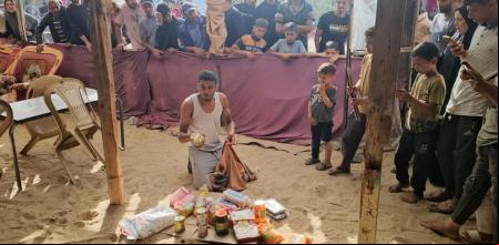 Un gazatí muestra lo recibido en una caja, en un campo de desplazados en Rafah, ayer (AFP)