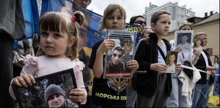 CHERNIHIV, UKRAINE - MAY 25: Children of Ukrainian prisoners of war hold photos of their fathers as they wait to see if they will be amongst the prisoner exchange arrivals on May 25, 2025 in Chernihiv, Ukraine. Today's swap brought home 303 soldiers, completing a 